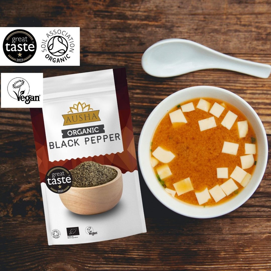 Organic Black Pepper 200g package with soup bowl on wooden table, certified organic and vegan.