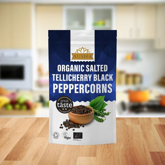 Organic Salted Tellicherry black peppercorns in a 100g bag, displayed in a kitchen setting, emphasizing their bold, savory flavor.