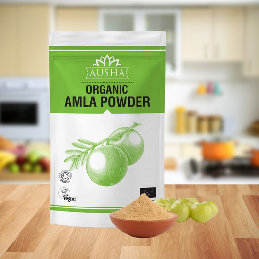 Organic Amla Powder in a green and white package with Indian gooseberry and powder, vegan and organic certified, on a kitchen counter.