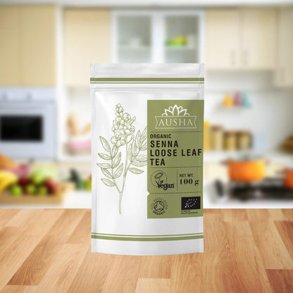 Organic Senna Tea 100g package on a kitchen countertop, certified organic and vegan.